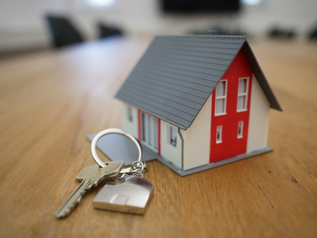 Chaves e uma miniatura no formato de uma casa, ambas sobre uma mesa de reuniões