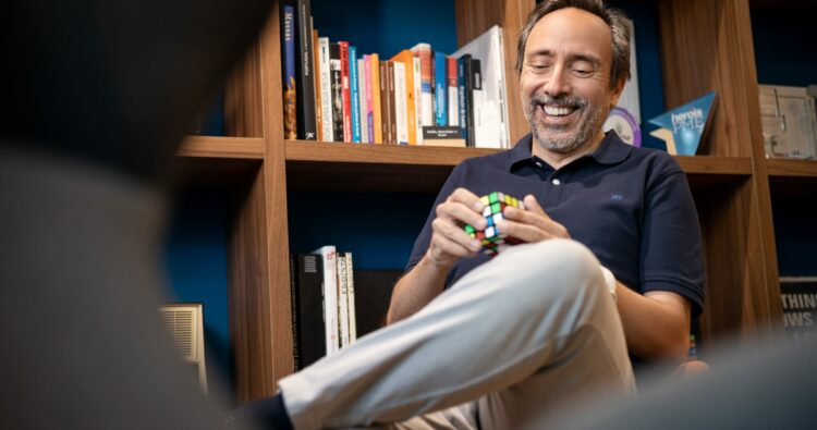 Massimo Forte, influenciador do mercado imobiliário, sentado em sua biblioteca a brincar com um cubo de Rubrik